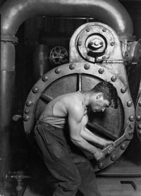 Photo of a man with a wrench working on a large piece of machinery.