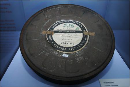 Photo of an old film reel behind glass in an exhibit.