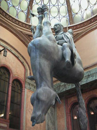 A sculpture of a man riding an upside-down horse. Sculpture by David Cerný, executed in foam, but made to look bronze.