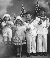 Old photograph of four children holding Norway flags.