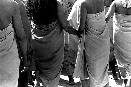 Low-angled photo of two women holding hands and wearing simple robes.