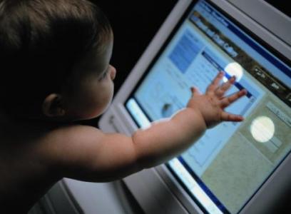 Image of a toddler touching a computer screen.